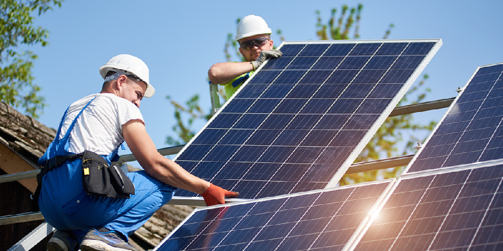Installers fitting solar panels on a roof using Esdec mounting systems